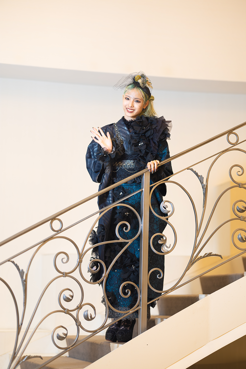 甘辛モノトーンの黒振袖を着た女性がこちらに手を振っている