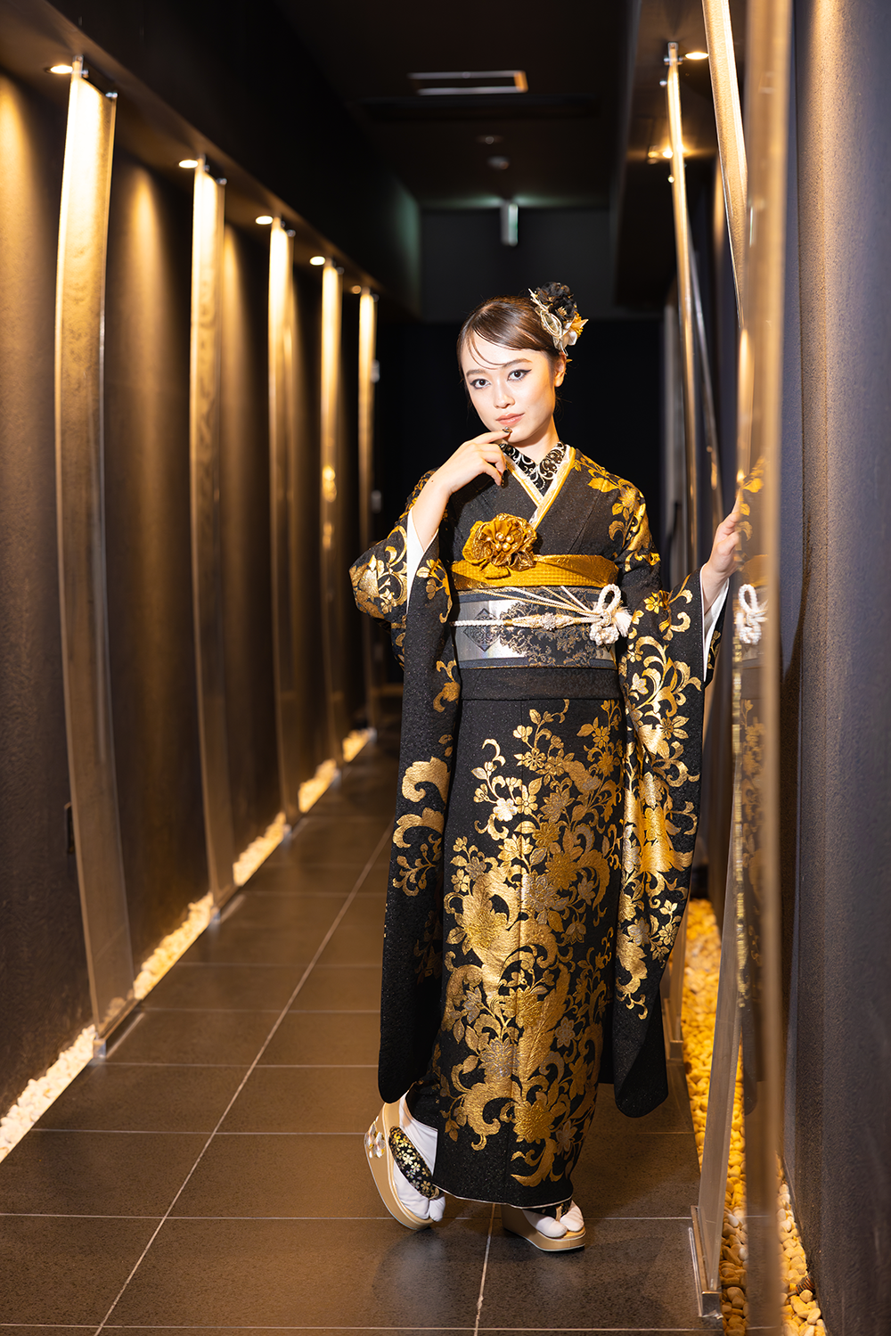 黒と金の振袖を着て女性が前撮りをしている